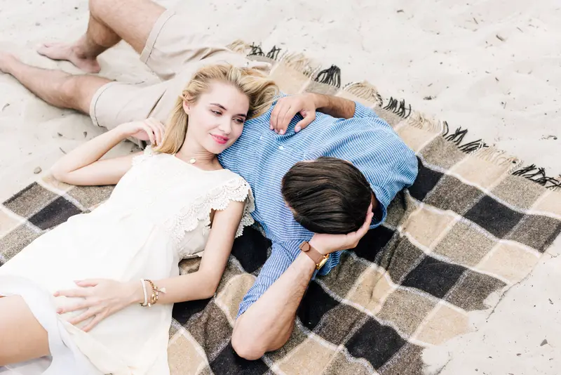 young couple lying together on checkered blanket 