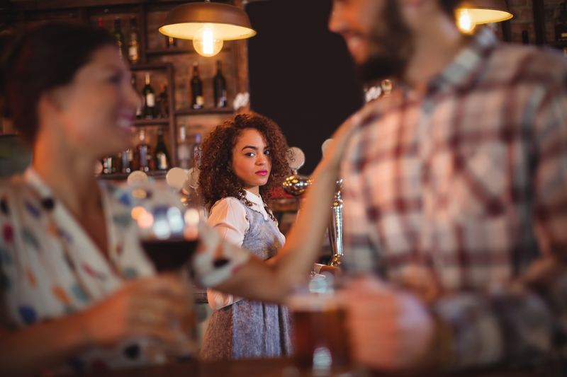 Jealous woman looking at couple flirting with each other in pub