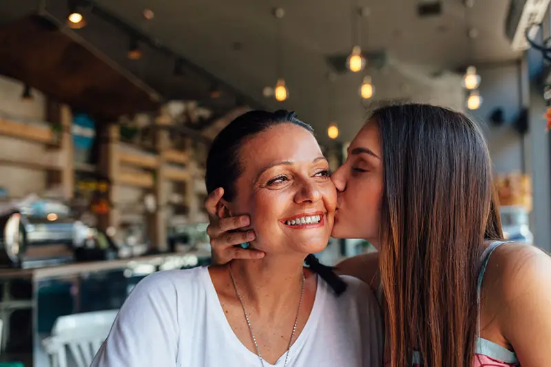 kvinna som kysser sin mamma som ler i baren