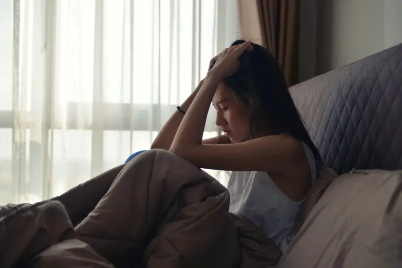 en deprimerad tjej i sängen hålls i hennes huvud