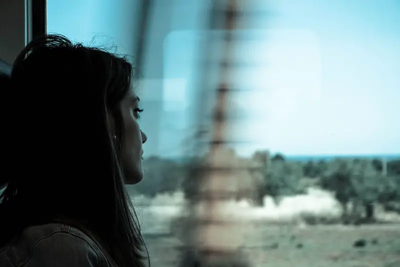 sorglig ung kvinna som sitter i tåget och tittar genom fönstret