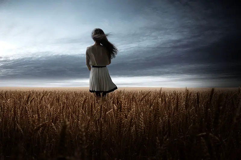 ung blond kvinna som står stilla mitt på fältet