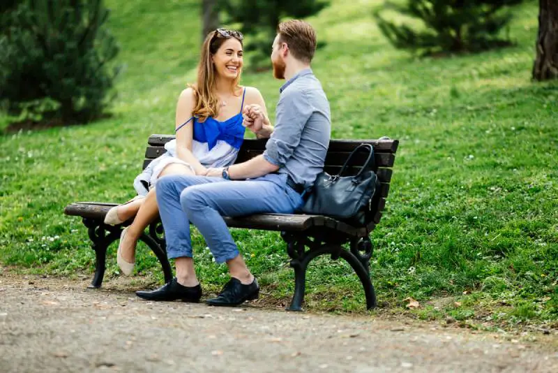Ett romantiskt älskande par som sitter på en parkbänk