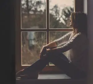 ledsen ung kvinna som sitter på fönstret