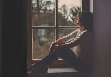 ledsen ung kvinna som sitter på fönstret