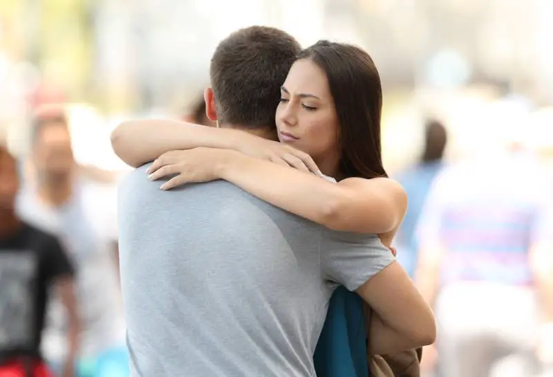 orolig kvinna som kramar hennes pojkvän utanför